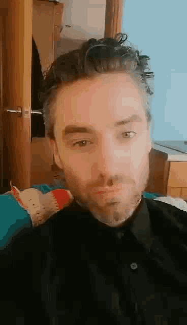 a man with a beard wearing a black shirt is looking at the camera .