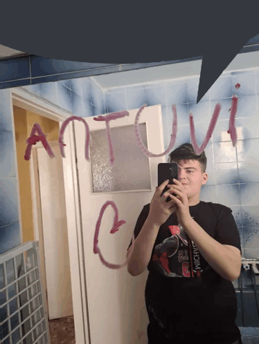 a young man taking a picture of himself with the word antoni written on the mirror