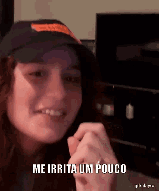 a woman wearing a black hat is smiling and says me irrita um pouco