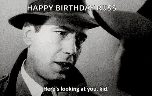 a black and white photo of a man in a hat saying happy birthday russ here 's looking at you kid .