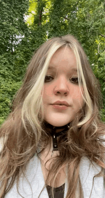 a girl with long hair and a choker around her neck looks at the camera