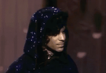 a close up of a person wearing a blue hooded jacket and a necklace .