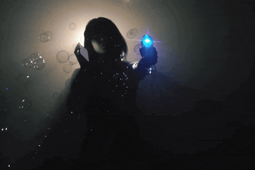 a woman in a dark room is holding a blue object
