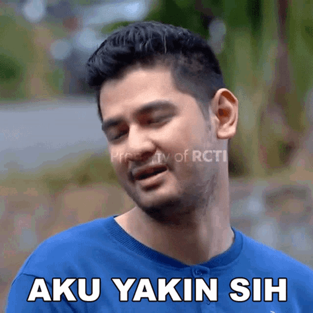 a man in a blue shirt has the words aku yakin sih on his face