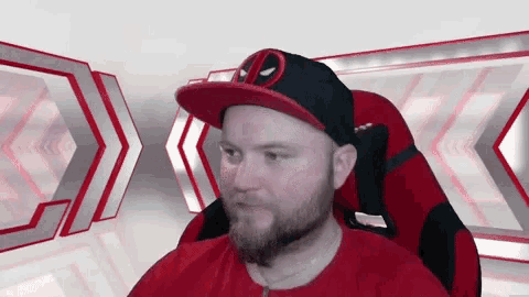 a man with a beard wearing a deadpool hat is sitting in a chair .