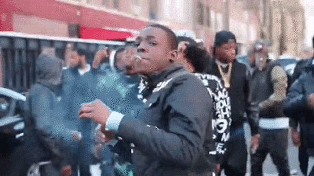 a man is smoking a cigarette while standing in a crowd of people .