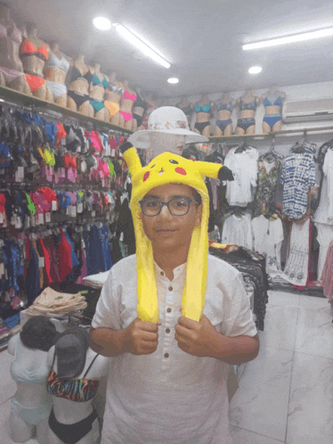 a boy wearing a yellow pikachu hat in a clothing store
