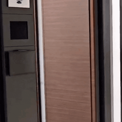 a black refrigerator with a wooden door is sitting in a kitchen .