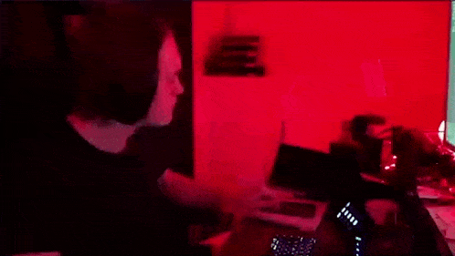 a person standing in front of a red wall with a laptop on the desk