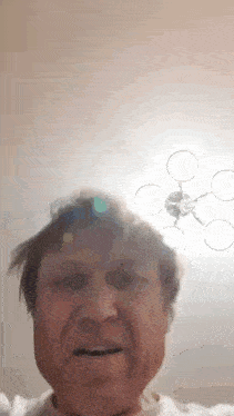 a close up of a man 's face with a drone flying overhead