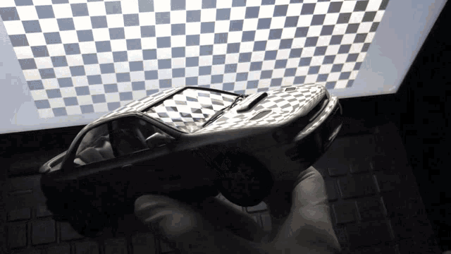 a person is holding a toy car in front of a checkered ceiling