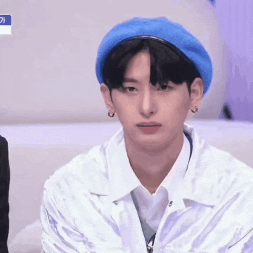 a young man wearing a blue hat and earrings