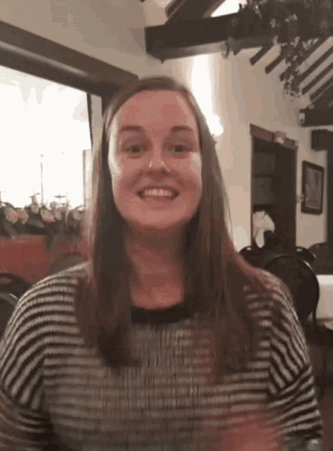 a woman wearing a black and white striped shirt smiles for the camera