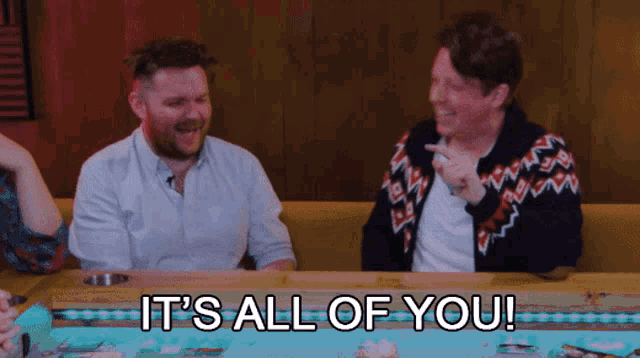 two men sitting at a table with the words " it 's all of you "