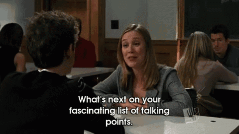 a woman sits at a table talking to a man and says what 's next on your fascinating list of talking points