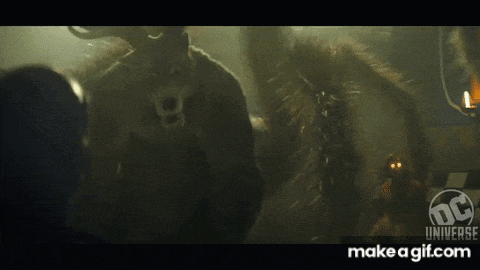 a couple of monsters are standing next to each other in a dark room in a movie .