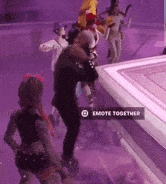 a group of people are dancing on a stage with a sign that says emote together on it .