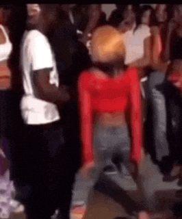 a woman in a red top is dancing in front of a crowd of people .