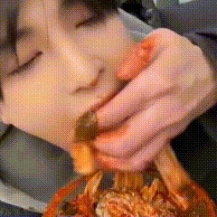 a close up of a person eating a hamburger with their eyes closed
