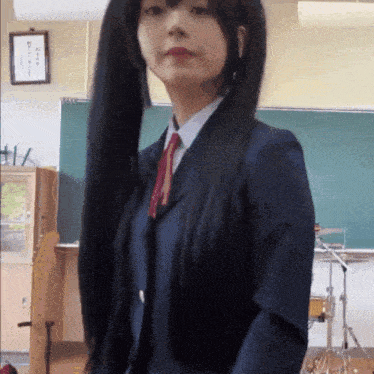 a girl in a suit and tie stands in front of a blackboard