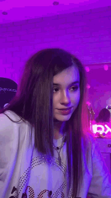 a girl with long hair is wearing a necklace and a white shirt .