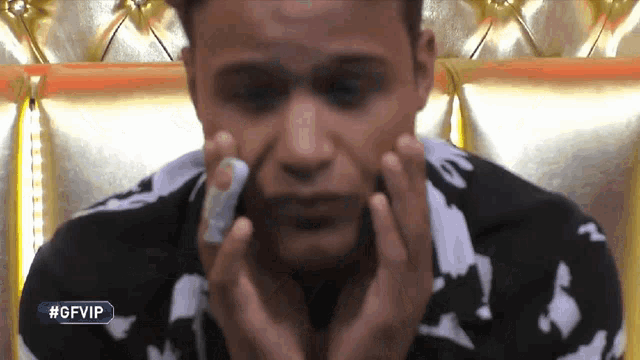 a man in a black and white shirt is covering his face with his hands and the gfvip logo is visible behind him