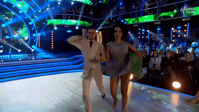 a man and a woman are dancing on a stage in front of a crowd that says dancing with the stars