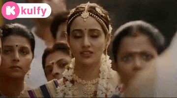 a woman in a wedding dress is standing in front of a crowd of people .