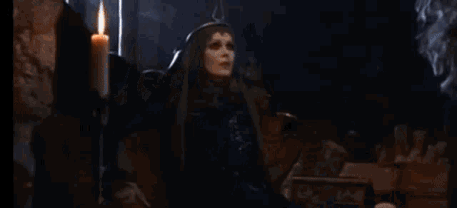 a woman with a crown on her head is standing next to a monster in a dark cave .