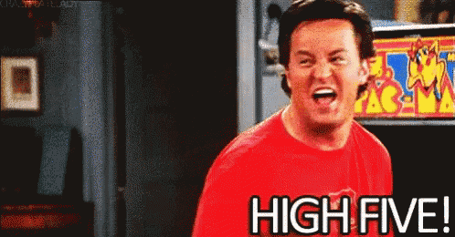 a man in a red shirt says high five in front of an arcade machine .