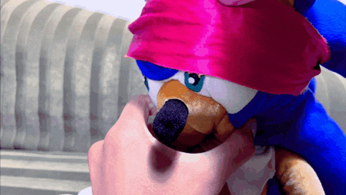 a person is holding a stuffed animal with a red ribbon around its head