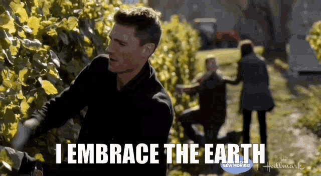 a man is kneeling down in front of a hedge with the words `` i embrace the earth '' written on the bottom .
