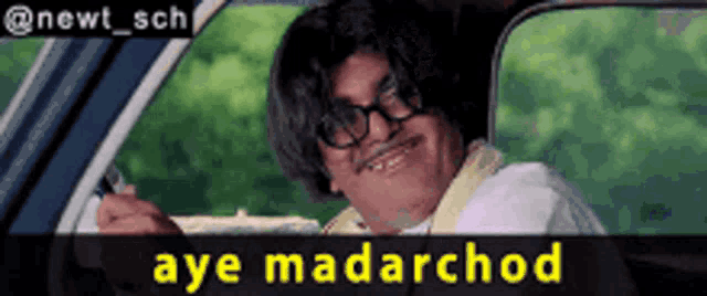 a man with glasses is smiling in a car with the words aye madarchod above him
