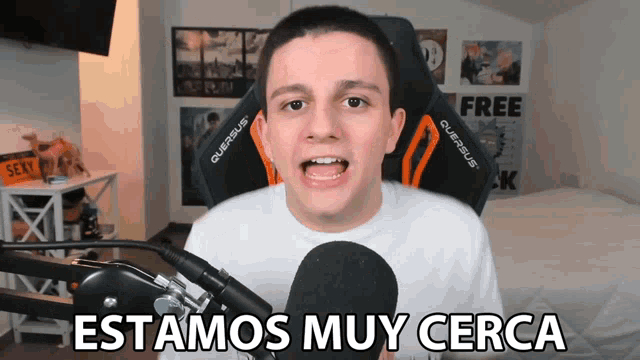 a young man in front of a microphone with the words estamos muy cerca on the bottom