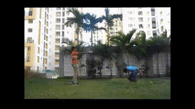 a man in a red shirt is playing frisbee in a park