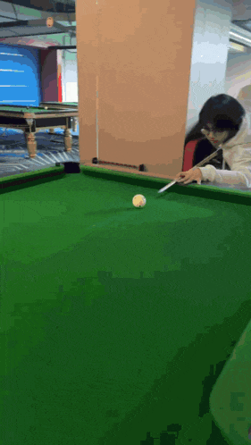 a woman is playing pool with a white ball