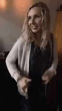 a woman in a white cardigan is dancing in a living room .