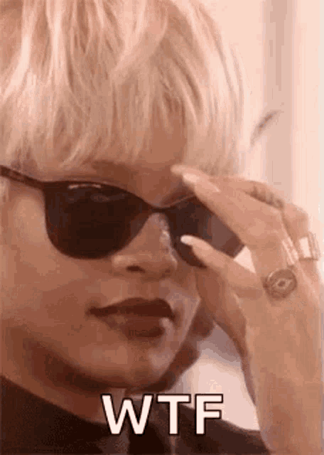 a woman wearing sunglasses and a ring is making a wtf face .