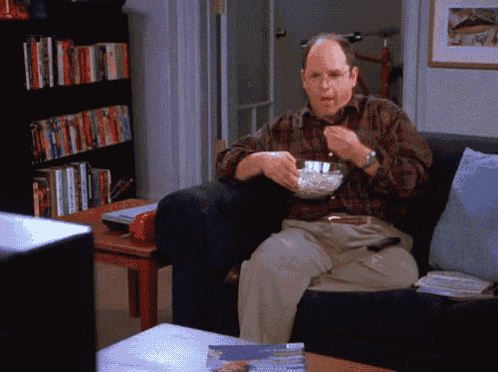 a man sitting on a couch with a bowl of popcorn in his hand