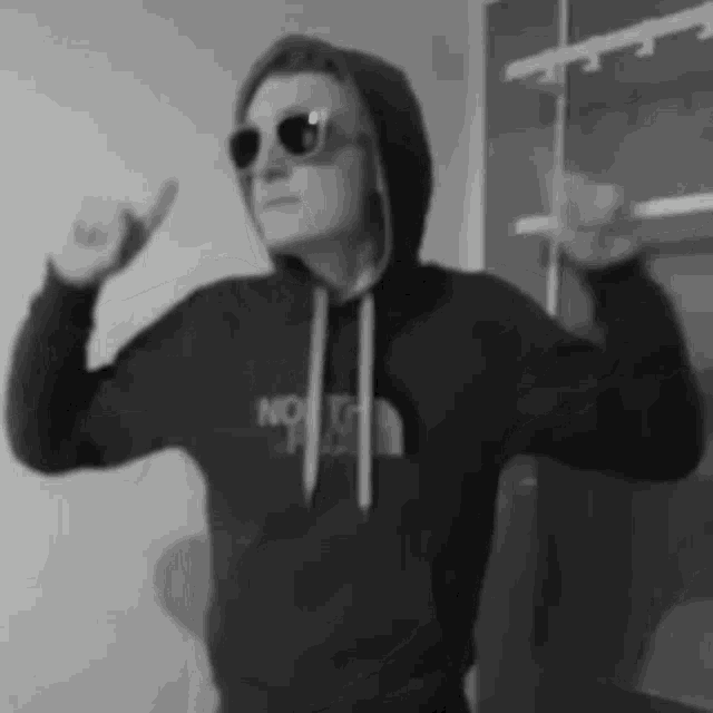 a man wearing sunglasses and a hoodie is making a funny face .