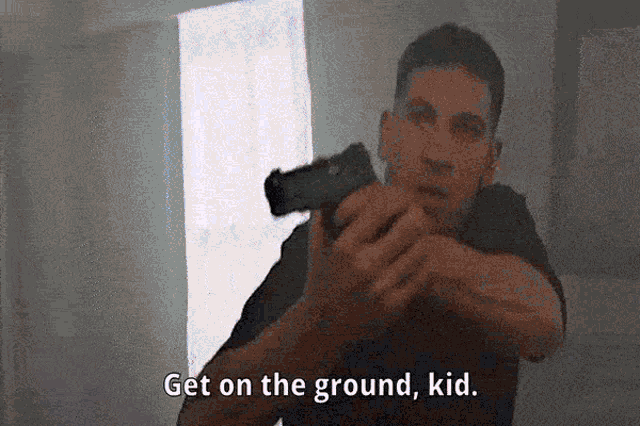 a man holding a gun with the words get on the ground kid below him