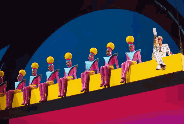 a woman sits on a yellow ledge next to a row of colorful people