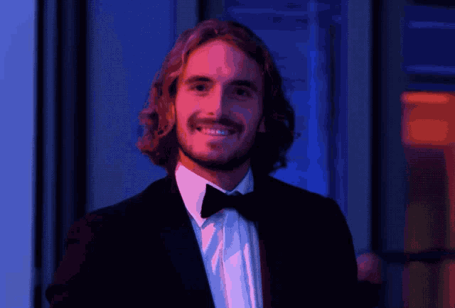 a man wearing a tuxedo and bow tie smiles