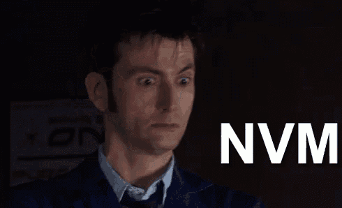 a man in a suit and tie is making a funny face and the word nvm is on the screen behind him .