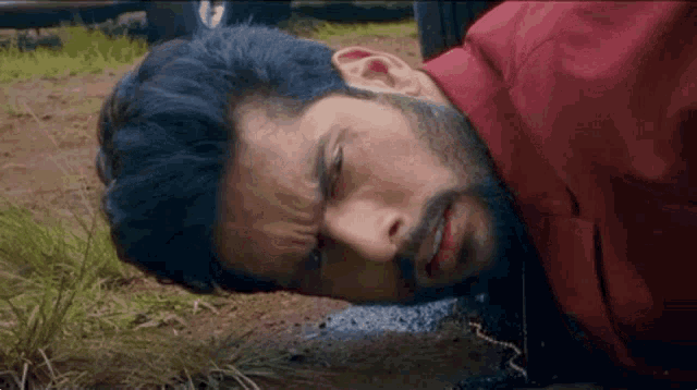 a man is laying on the ground with his head in the dirt .