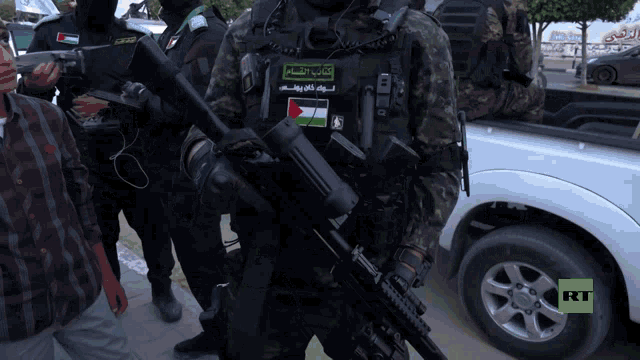 a group of soldiers are standing in front of a white truck with rt on the screen