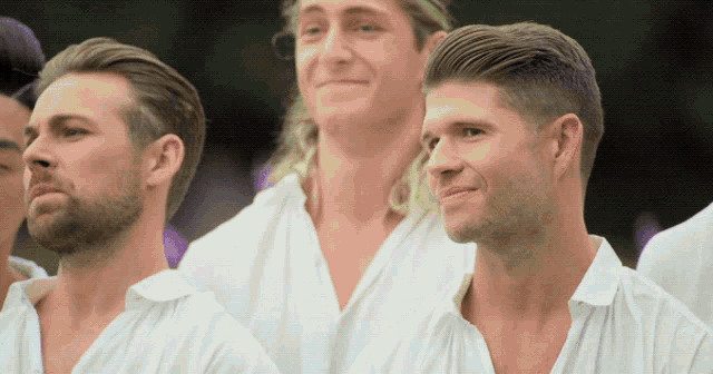a group of men in white shirts are standing in a line