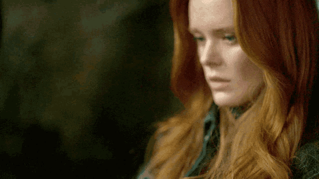 a close up of a woman 's face with red hair and green eyes