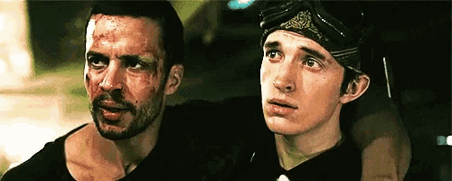 two men are sitting next to each other with one wearing a bandana on his head