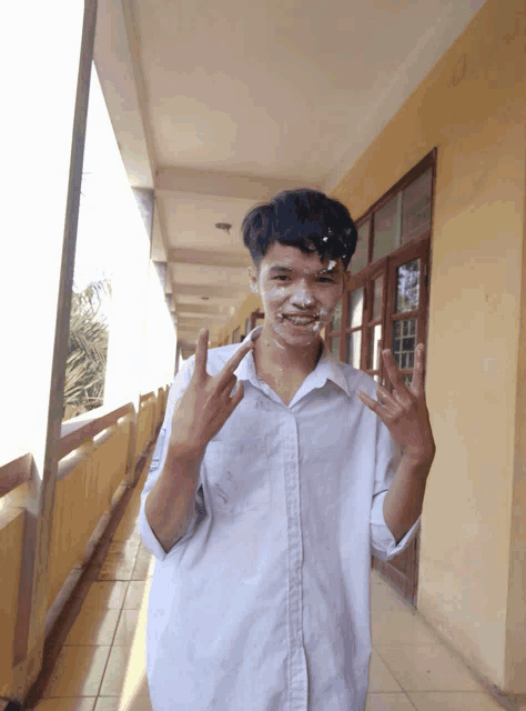 a young man with white paint on his face is making a devil horns gesture